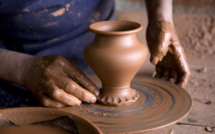 Artesano de la alfarería en el torno con arcilla.